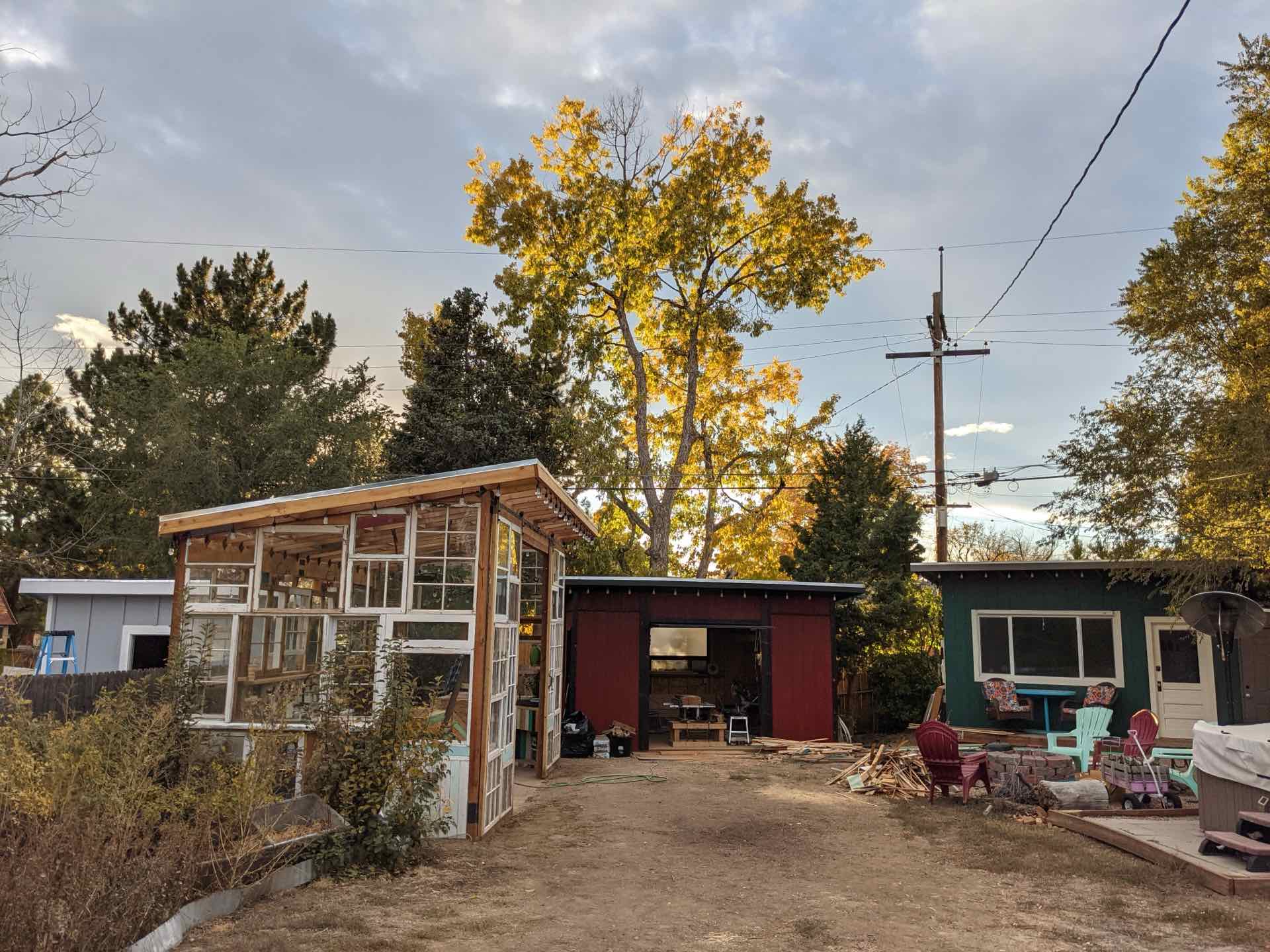 The window shed beside the red tool shed under a yellow autumn tree